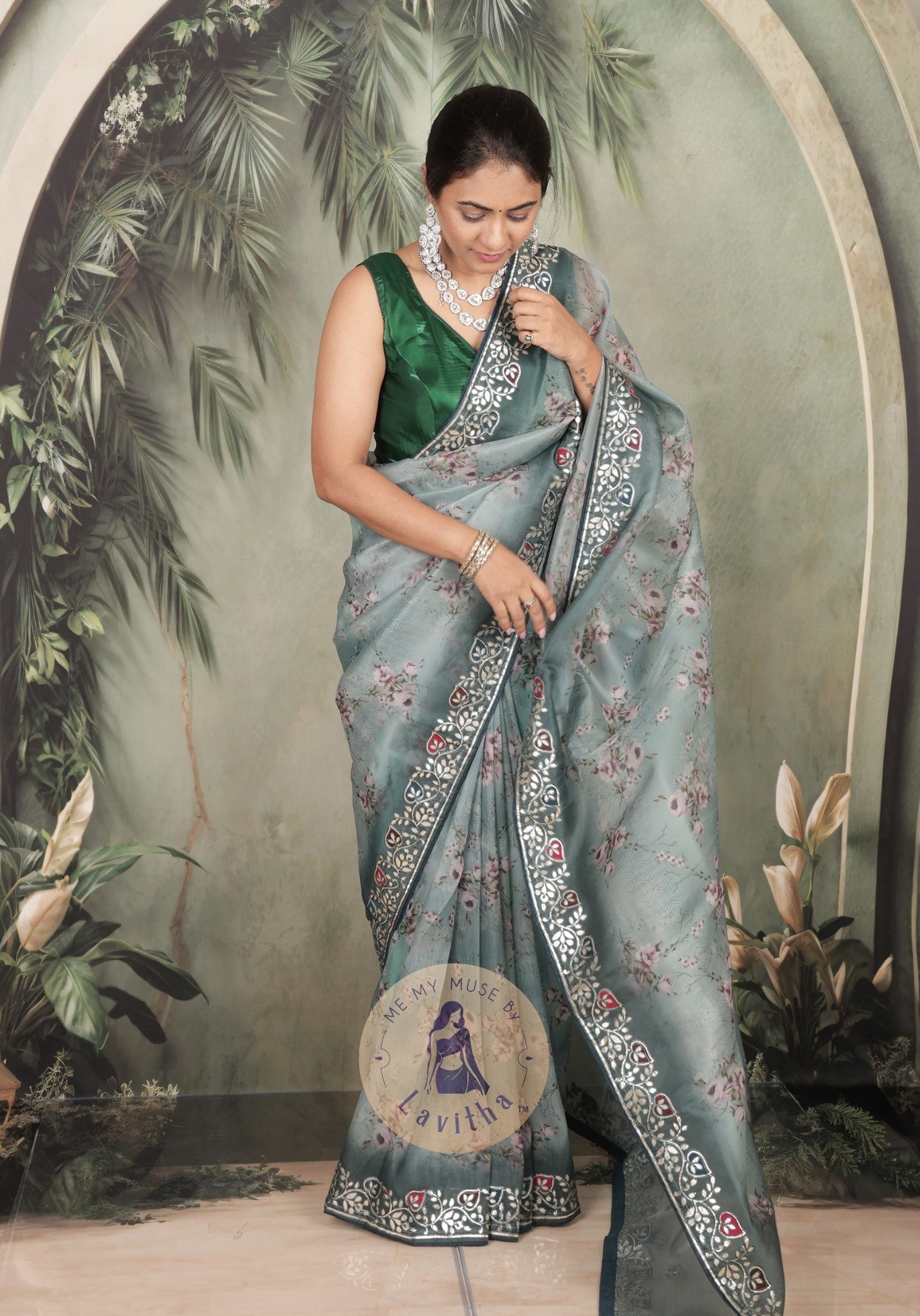 Our muse is wearing a rich premium floral digital printed organza Pastel Greyish Green saree with Gota Patti work on the border and designer pallu. This festive-wear saree is part of the Dilqash collection of Me My Muse by Lavitha