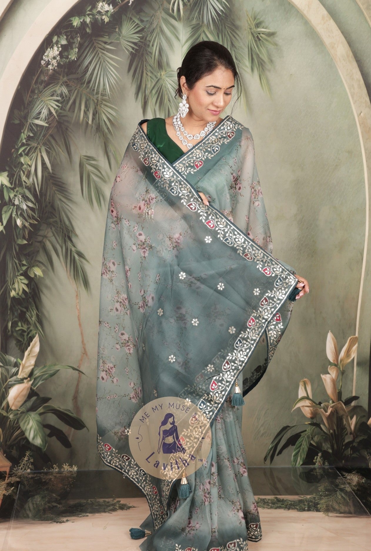 Our muse is wearing a rich premium floral digital printed organza Pastel Greyish Green saree with Gota Patti work on the border and designer pallu. This festive-wear saree is part of the Dilqash collection of Me My Muse by Lavitha
