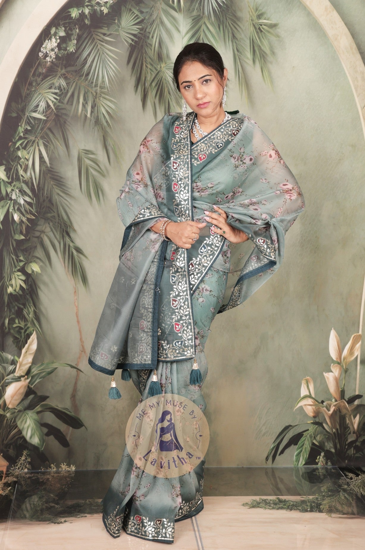 Our muse is wearing a rich premium floral digital printed organza Pastel Greyish Green saree with Gota Patti work on the border and designer pallu. This festive-wear saree is part of the Dilqash collection of Me My Muse by Lavitha