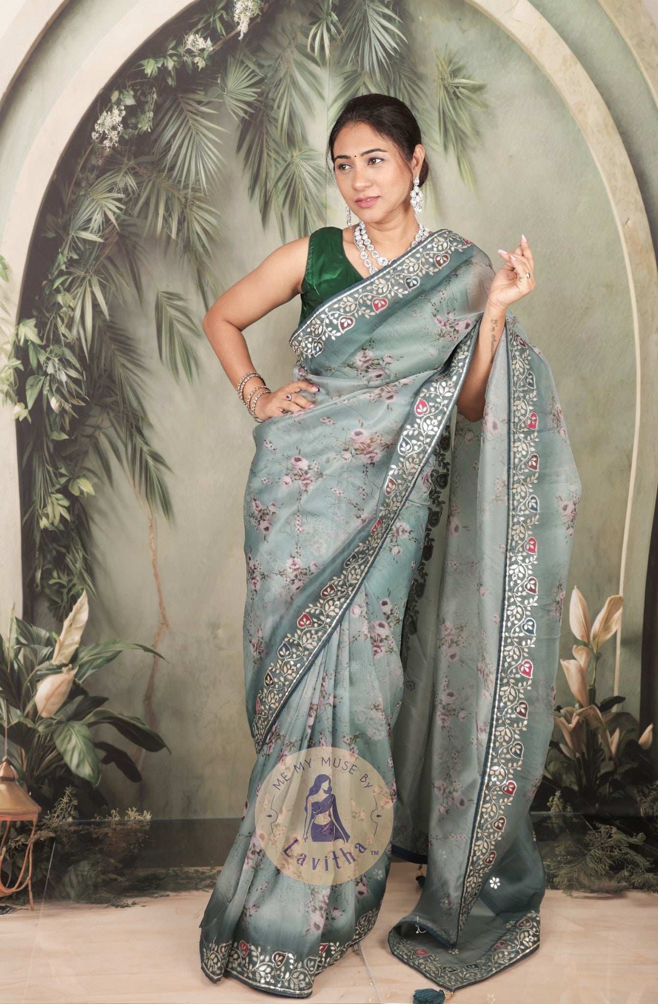 Our muse is wearing a rich premium floral digital printed organza Pastel Greyish Green saree with Gota Patti work on the border and designer pallu. This festive-wear saree is part of the Dilqash collection of Me My Muse by Lavitha