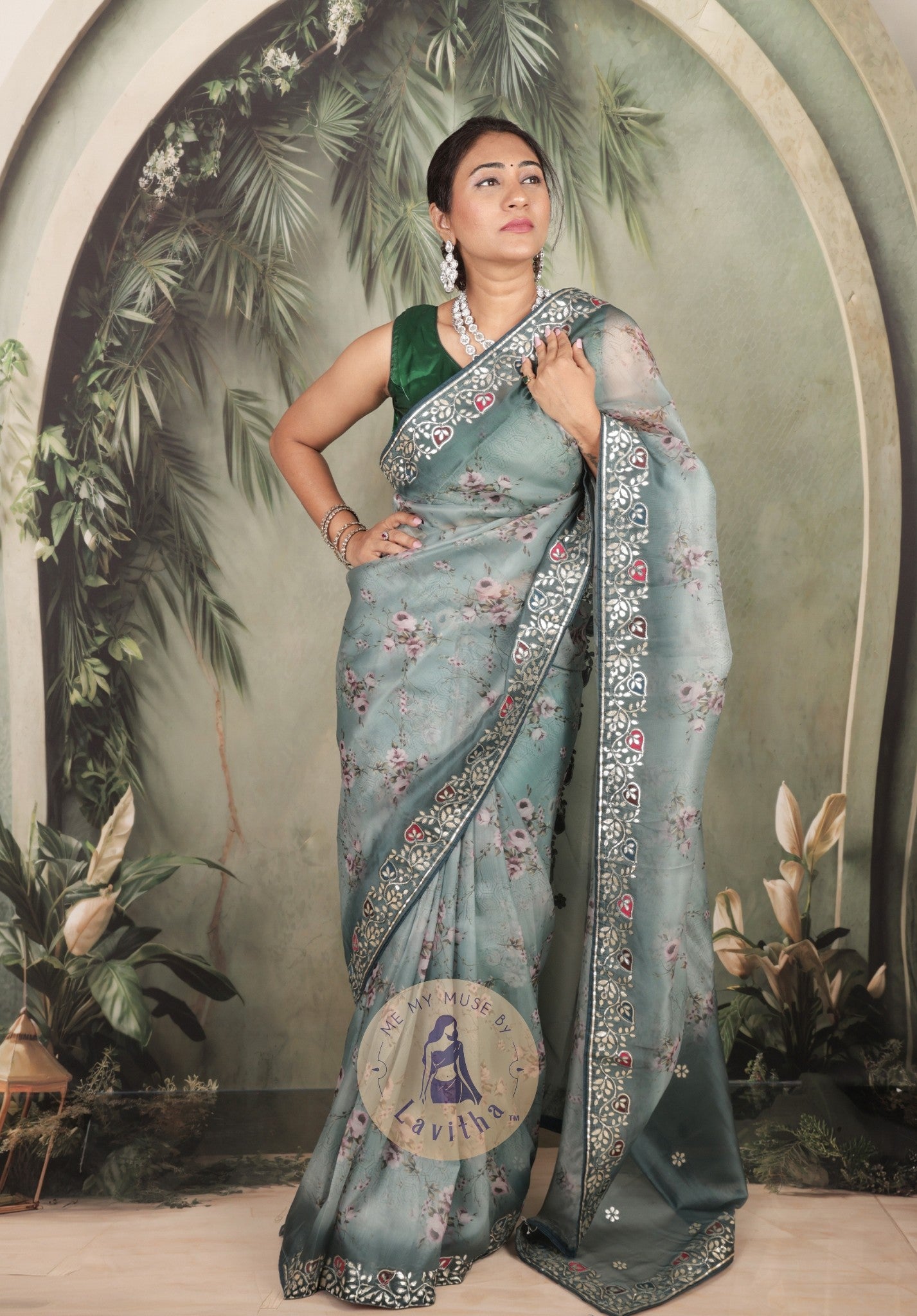 Our muse is wearing a rich premium floral digital printed organza Pastel Greyish Green saree with Gota Patti work on the border and designer pallu. This festive-wear saree is part of the Dilqash collection of Me My Muse by Lavitha